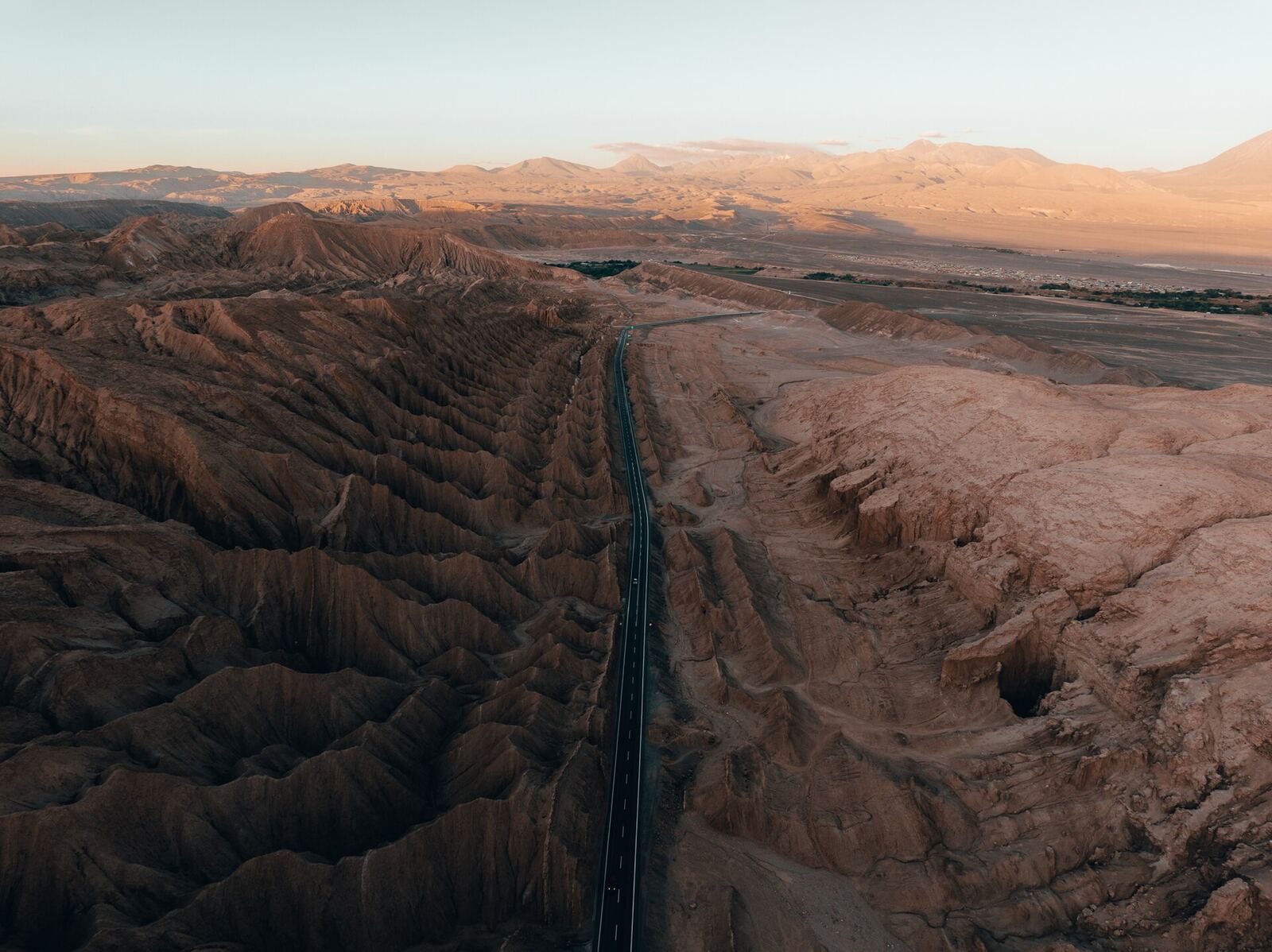 Captured in the silent immensity of the desert, this image presents a solitary highway carving its way like a dark incision through the undulating ochre dunes. The aerial perspective emphasizes the vastness of the landscape and the faint presence of the road, inviting reflection on the journey, solitude, and the imposing beauty of the aridity in San Pedro de Atacama.