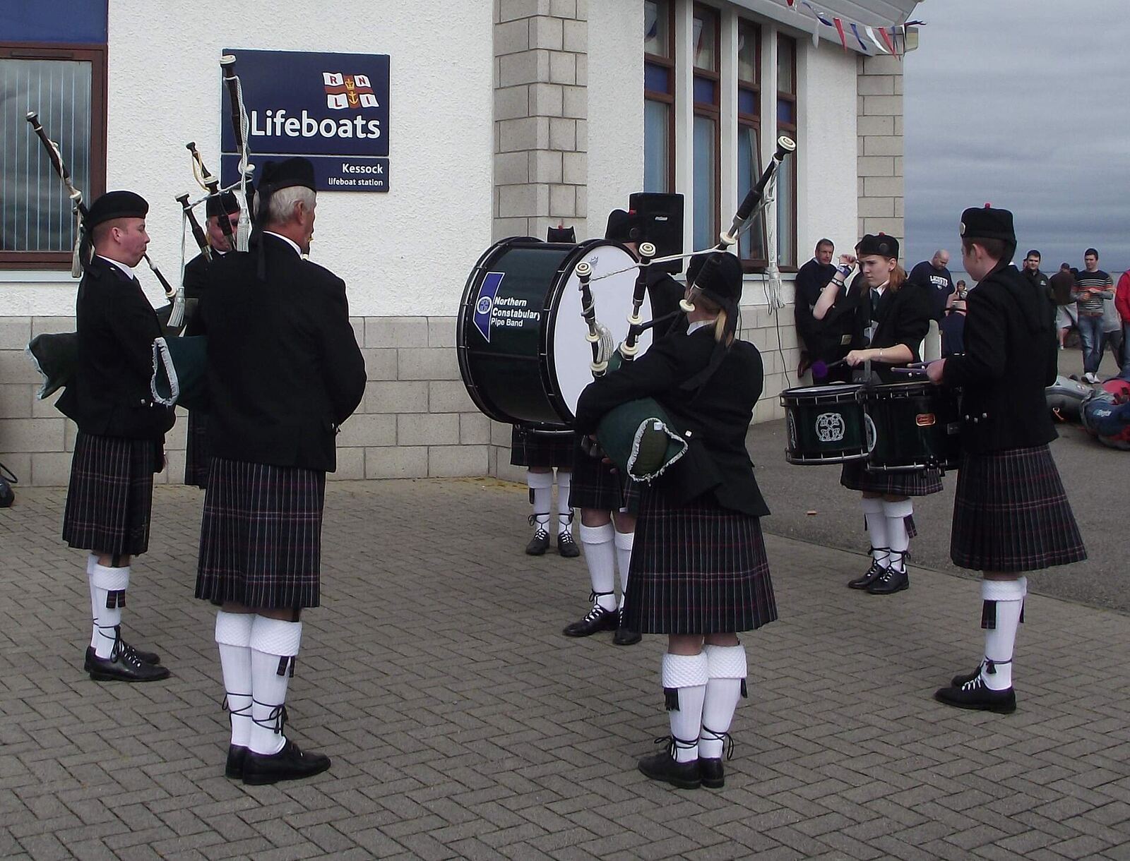 The Band playing outside the west side of the Lifeboat Station, slightly sheltered from the breeze off the sea! The village of Kessock (a.k.a. North Kessock) lies directly across the Beauly Firth from the City of Inverness. Until fairly recently, a ferry ran between the two, but since 1982 the imposing Kessock Bridge (carrying the A9 trunk road north from Inverness) has joined the two communities. en.wikipedia.org/wiki/Kessock_Bridge Kessock lies directly opposite the mouth of the River Ness, and Inverness Harbour and Marina, and the entrance to the Caledonian Canal is close by too. As a busy arm of the North Sea/Moray firth., the Beauly Firth is an important maritime route, both for commercial and leisure traffic. It took a long time to get a lifeboat based in the Inverness area but now that we do have the facility, locals are extremely proud - and supportive - of the Kessock lifeboat and its brave crew. The Lifeboat station is located at Craigton Point, directly under the north end of the Kessock Bridge. Several Band members have family or friends in the crew, hence we were delighted to be able to support and assist at the RNLI Kessock Station open day today (24th August 2013) by providing a mini-band to entertain the visitors. Kessock is one of Scotland’s youngest lifeboat stations, operating an inshore B class Atlantic 75 lifeboat – “The Moray Dolphin”. For over 10 years the lifeboat crews have launched the lifeboats, not only to save lives at sea but also to save lives inland during flooding. rnli.org/findmynearest/station/Pages/Kessock-Lifeboat-Sta...