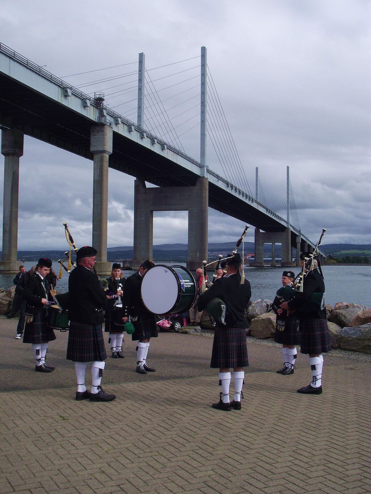 Playing in the shadow of the Kessock Bridge, outside the Lifeboat Station. The village of Kessock (a.k.a. North Kessock) lies directly across the Beauly Firth from the City of Inverness. Until fairly recently, a ferry ran between the two, but since 1982 the imposing Kessock Bridge (carrying the A9 trunk road north from Inverness) has joined the two communities. en.wikipedia.org/wiki/Kessock_Bridge Kessock lies directly opposite the mouth of the River Ness, and Inverness Harbour and Marina, and the entrance to the Caledonian Canal is close by too. As a busy arm of the North Sea/Moray firth., the Beauly Firth is an important maritime route, both for commercial and leisure traffic. It took a long time to get a lifeboat based in the Inverness area but now that we do have the facility, locals are extremely proud - and supportive - of the Kessock lifeboat and its brave crew. The Lifeboat station is located at Craigton Point, directly under the north end of the Kessock Bridge. Several Band members have family or friends in the crew, hence we were delighted to be able to support and assist at the RNLI Kessock Station open day today (24th August 2013) by providing a mini-band to entertain the visitors. Kessock is one of Scotland’s youngest lifeboat stations, operating an inshore B class Atlantic 75 lifeboat – “The Moray Dolphin”. For over 10 years the lifeboat crews have launched the lifeboats, not only to save lives at sea but also to save lives inland during flooding. rnli.org/findmynearest/station/Pages/Kessock-Lifeboat-Sta...
